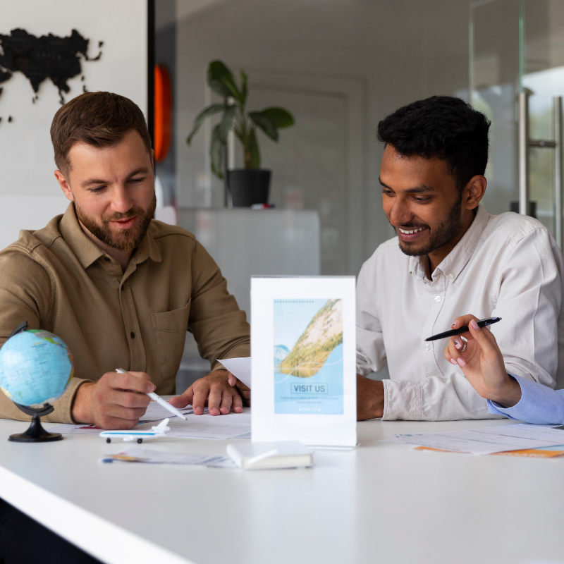 Two professionals consulting over paperwork at a desk.