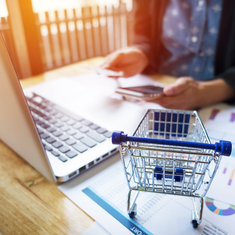 Shopping cart placed beside a laptop representing business accounting work.