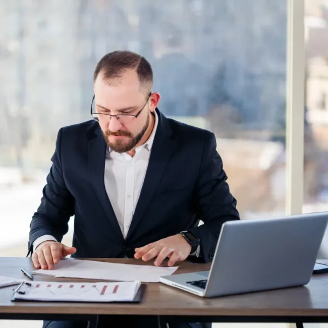Financial consultant analysing reports with laptop in modern office