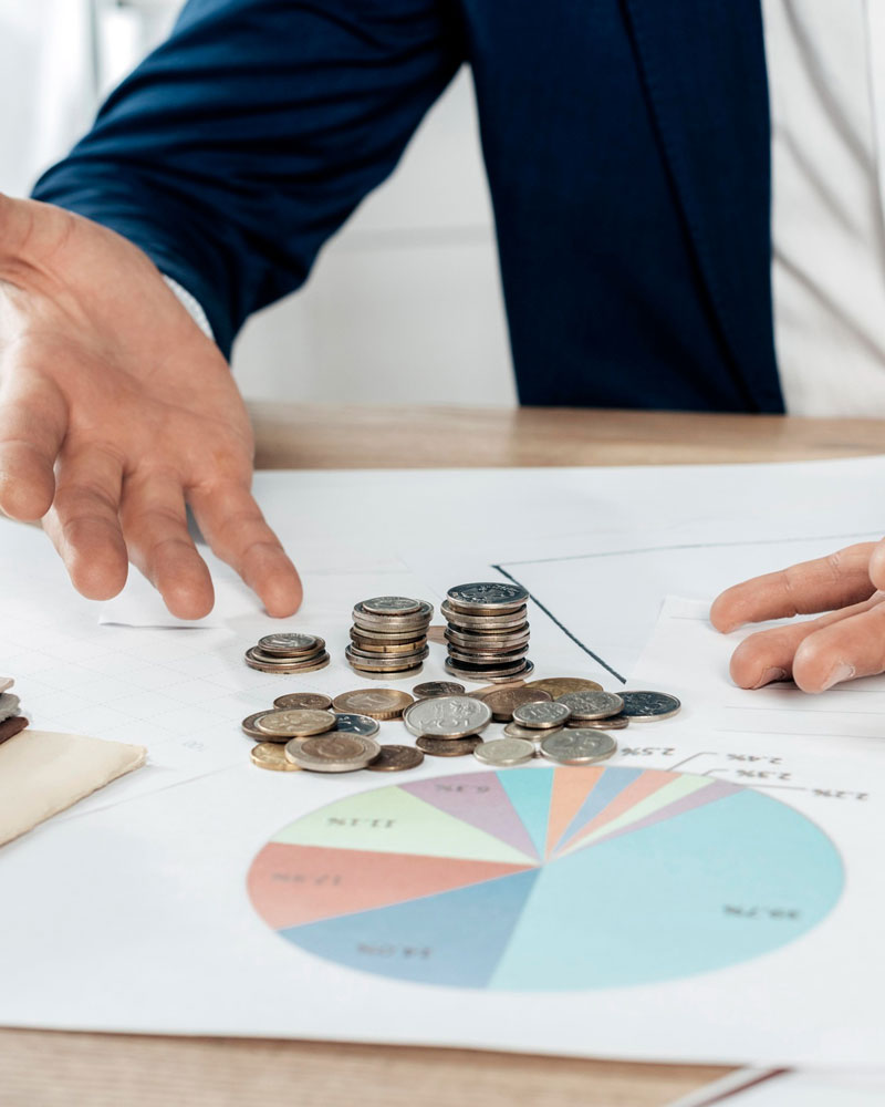 Financial analysis with coins and charts on a desk.