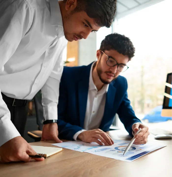 Two business professionals analyzing charts and reports together during a financial planning meeting.