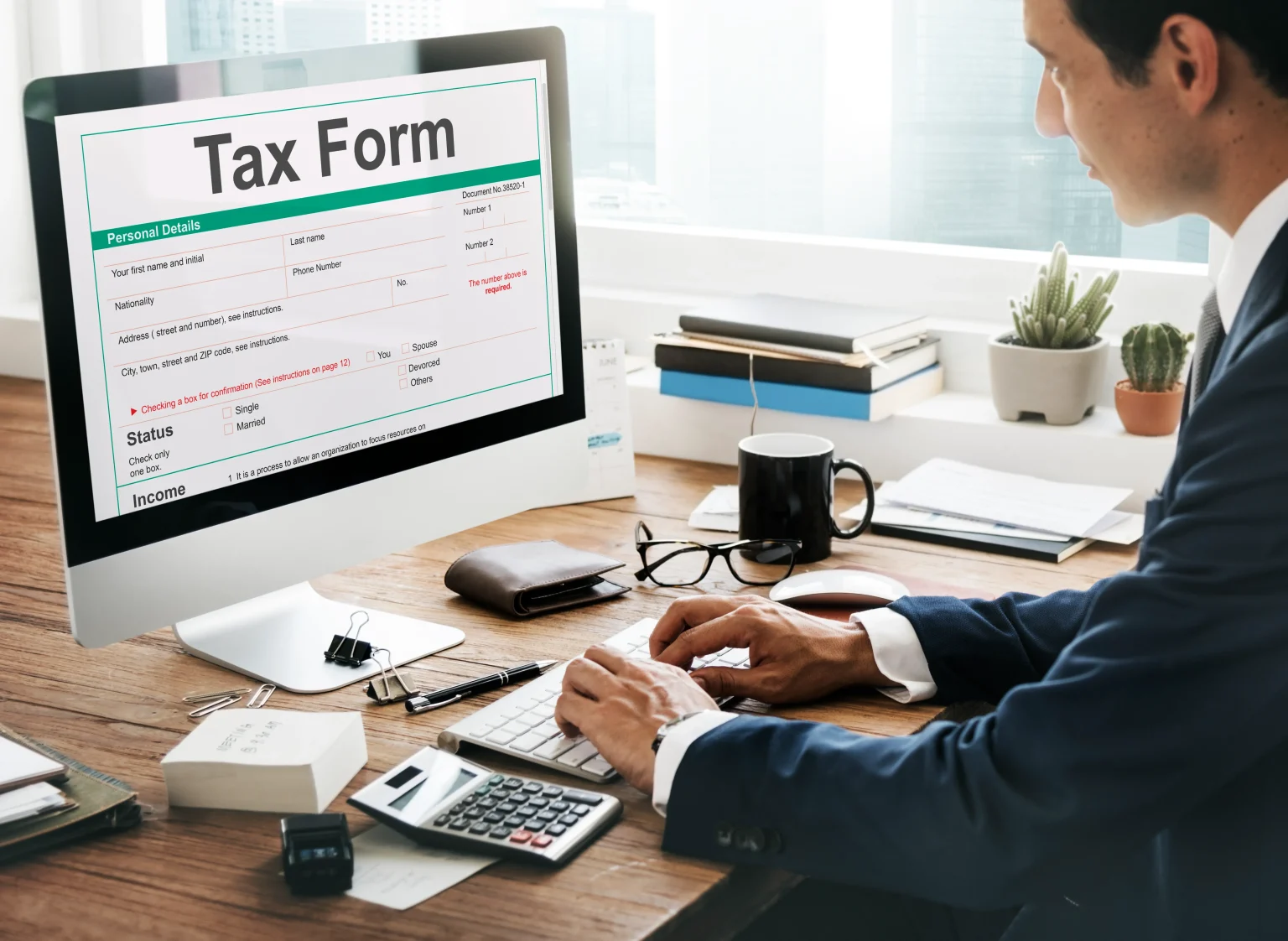 Business professional filling tax form on computer with calculator at office desk