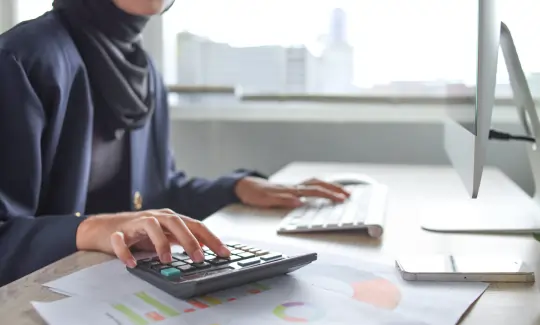 Business professional analyzing financial reports and using a calculator, representing research on whether the UAE has corporate tax.